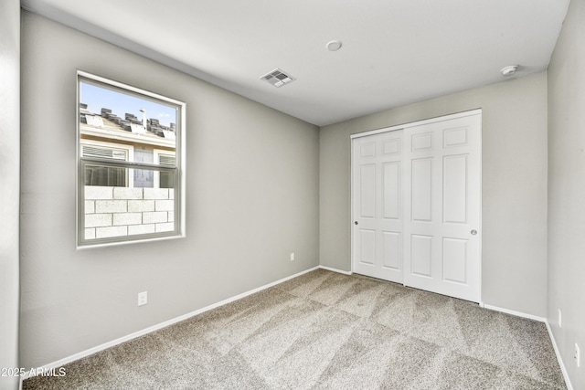 unfurnished bedroom with carpet flooring, baseboards, visible vents, and a closet