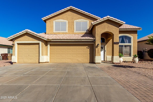 mediterranean / spanish home featuring a tile roof, driveway, an attached garage, and stucco siding