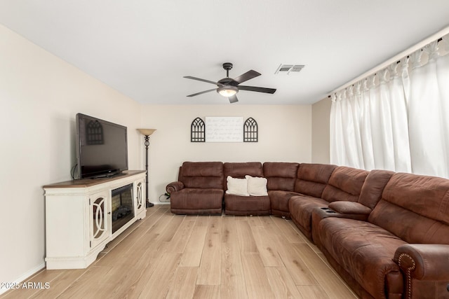 living area with light wood-type flooring, visible vents, and a ceiling fan