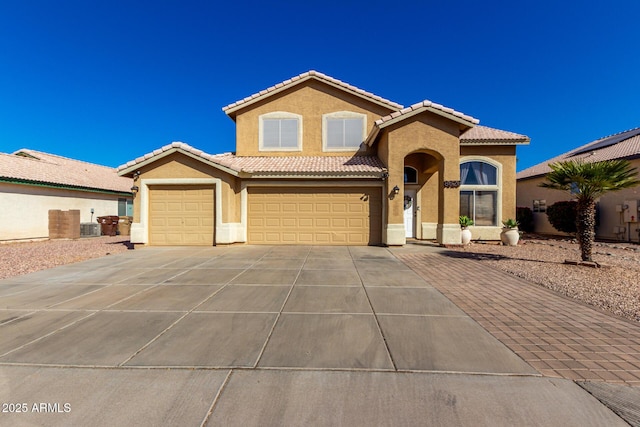 mediterranean / spanish house with driveway, a tiled roof, a garage, and stucco siding