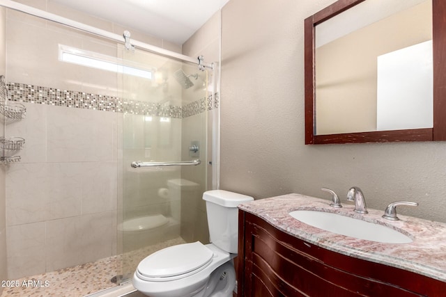 bathroom with vanity, a shower stall, and toilet