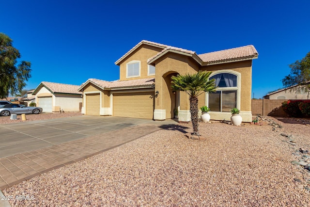 mediterranean / spanish-style house with concrete driveway, a tiled roof, an attached garage, fence, and stucco siding