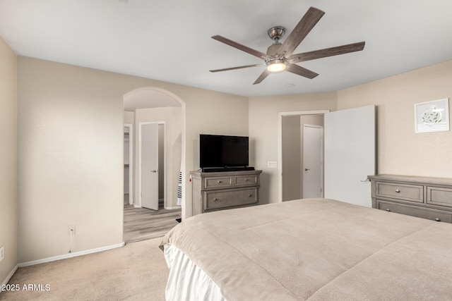 bedroom with arched walkways, light carpet, ceiling fan, and baseboards