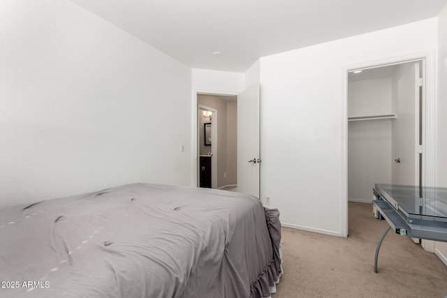 bedroom with baseboards, a walk in closet, a closet, and light colored carpet