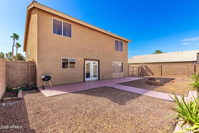 rear view of house featuring a patio area, an outdoor fire pit, stucco siding, and french doors