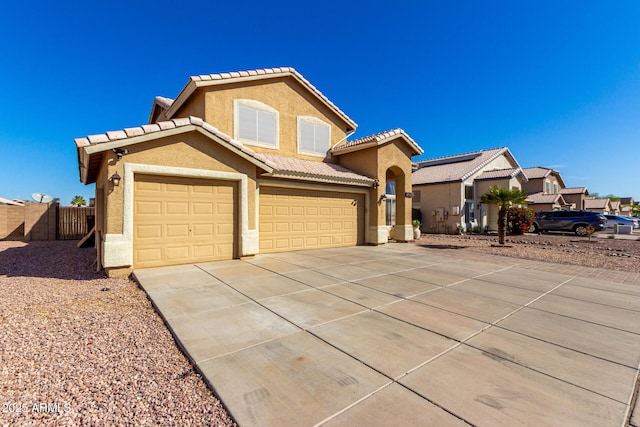 mediterranean / spanish-style house featuring stucco siding, concrete driveway, fence, a garage, and a tiled roof