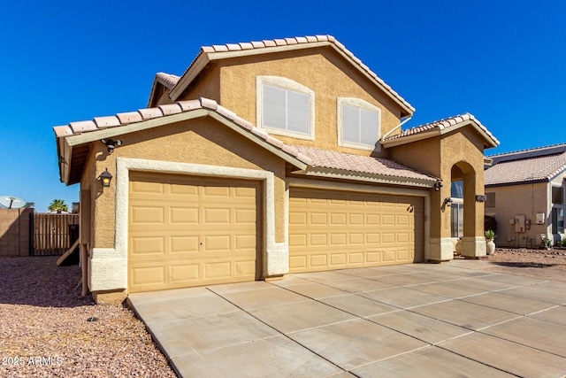 view of front facade featuring driveway, a tiled roof, a garage, and stucco siding