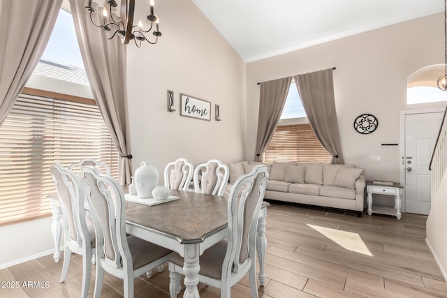 dining space featuring baseboards, a high ceiling, wood finish floors, and a notable chandelier