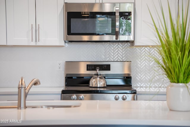 475 S Soho Ln Unit 35, Chandler, AZ 85225 - kitchen featuring a sink, white cabinets, light countertops, appliances with stainless steel finishes, and tasteful backsplash