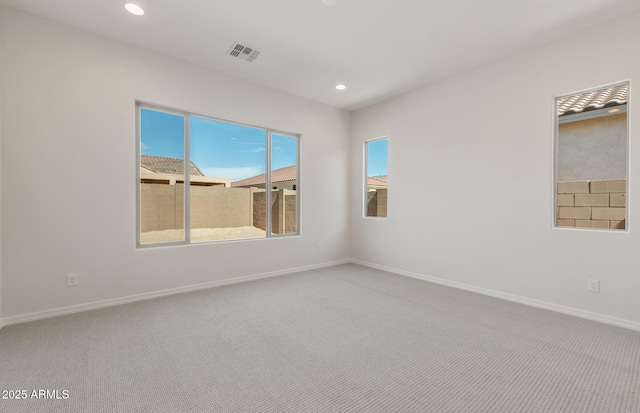 carpeted spare room featuring baseboards, visible vents, and recessed lighting