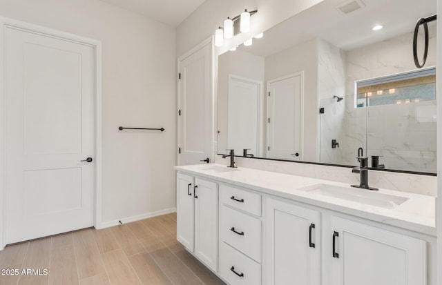 full bathroom with a marble finish shower, double vanity, a sink, and visible vents