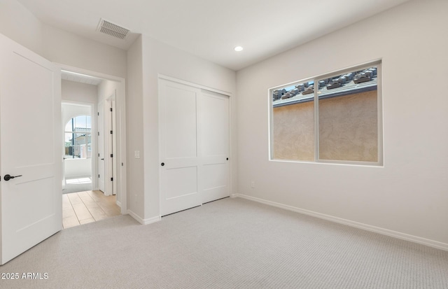 unfurnished bedroom featuring recessed lighting, a closet, light colored carpet, visible vents, and baseboards