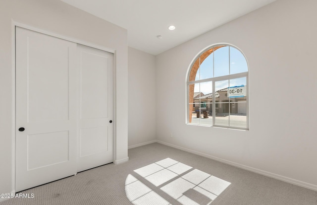 unfurnished bedroom with baseboards, a closet, and light colored carpet