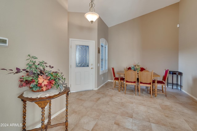 dining area featuring baseboards and high vaulted ceiling
