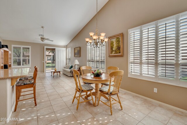 dining room featuring ceiling fan with notable chandelier, light tile patterned floors, and high vaulted ceiling