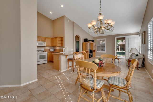 dining space with an inviting chandelier, vaulted ceiling, light tile patterned flooring, and sink