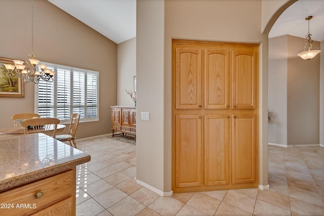 kitchen with arched walkways, light stone countertops, light tile patterned flooring, and light brown cabinetry