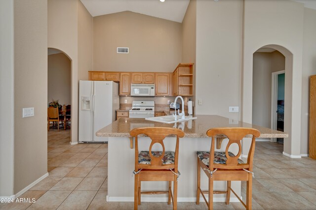 kitchen with light tile patterned flooring, high vaulted ceiling, white appliances, kitchen peninsula, and a breakfast bar area