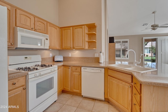 kitchen featuring a peninsula, a sink, light brown cabinetry, and white appliances