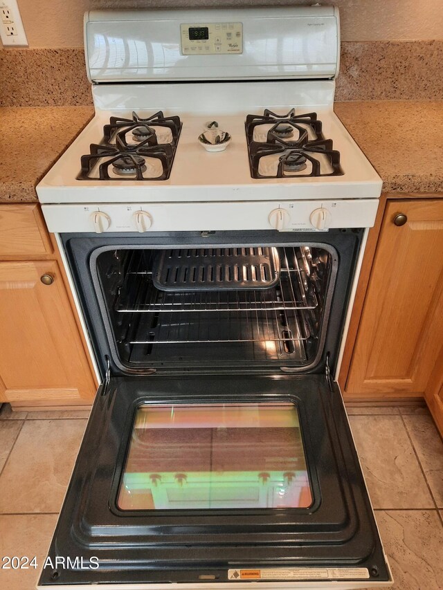 interior details featuring white gas stove and light tile patterned flooring