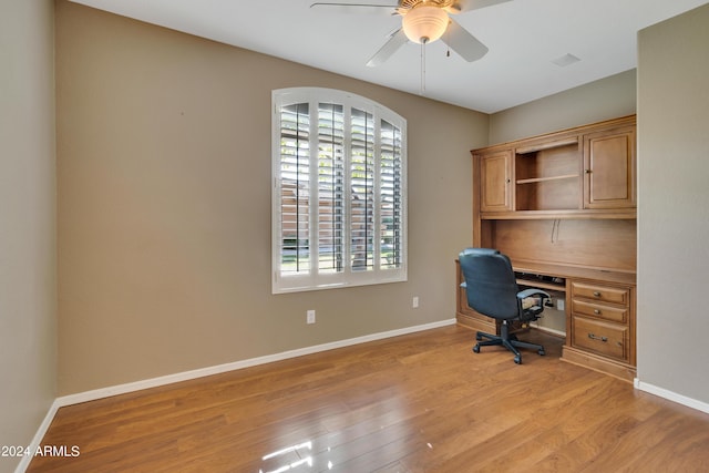 unfurnished office with baseboards, light wood-style flooring, and a ceiling fan