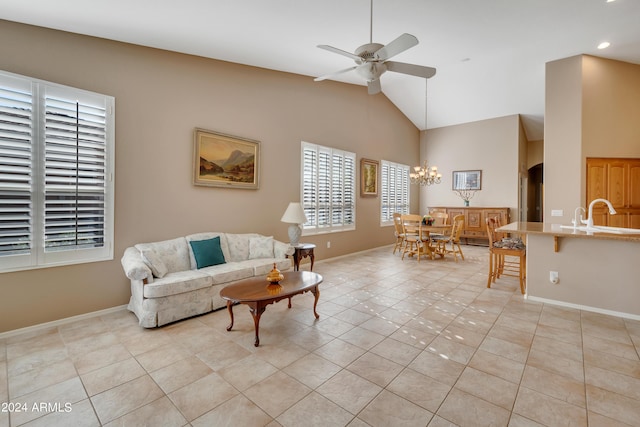 living area with light tile patterned flooring, ceiling fan with notable chandelier, high vaulted ceiling, and baseboards