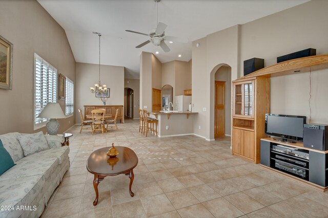 living room featuring ceiling fan with notable chandelier, high vaulted ceiling, light tile patterned flooring, and sink