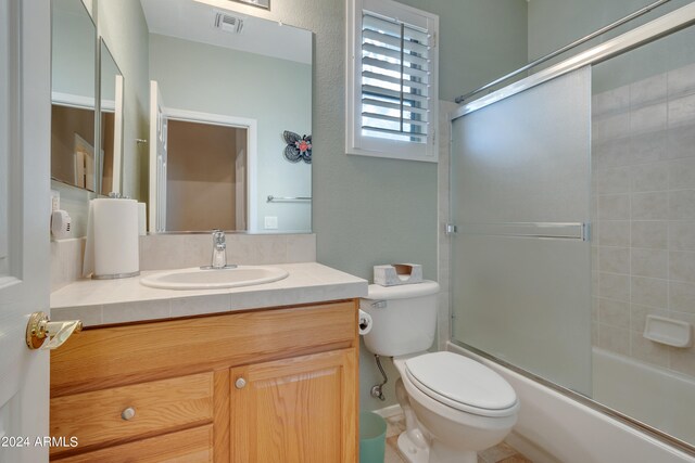 full bathroom featuring shower / bath combination with glass door, vanity, and toilet