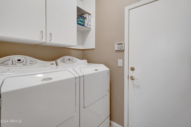 laundry room featuring washer and dryer and cabinets