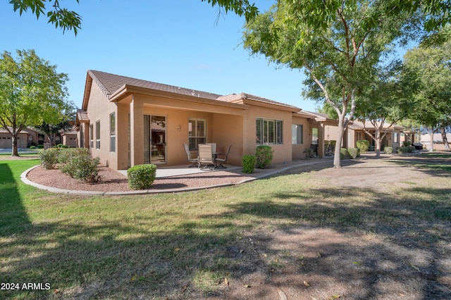 back of property with a lawn, a tile roof, stucco siding, and a patio