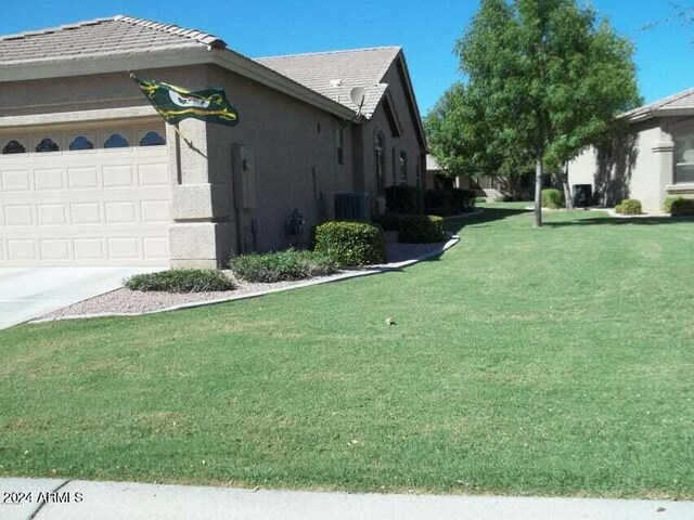 view of property exterior with a garage, central AC unit, and a yard