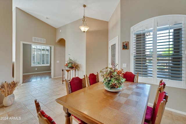 dining space with high vaulted ceiling, tile patterned flooring, baseboards, visible vents, and arched walkways