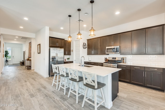 kitchen featuring light wood-type flooring, sink, hanging light fixtures, stainless steel appliances, and dark brown cabinetry