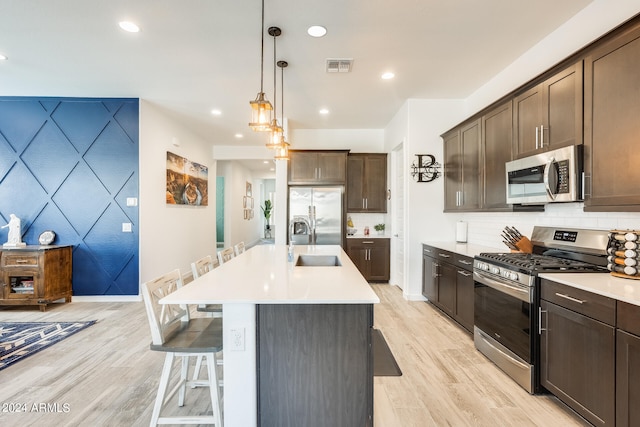 kitchen featuring pendant lighting, sink, a kitchen breakfast bar, light hardwood / wood-style flooring, and appliances with stainless steel finishes