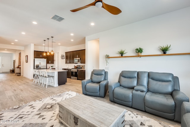 living room featuring ceiling fan, sink, and light hardwood / wood-style floors