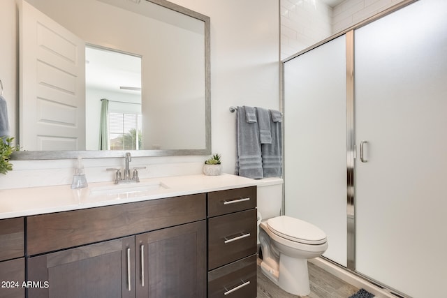 bathroom with a shower with shower door, vanity, and toilet