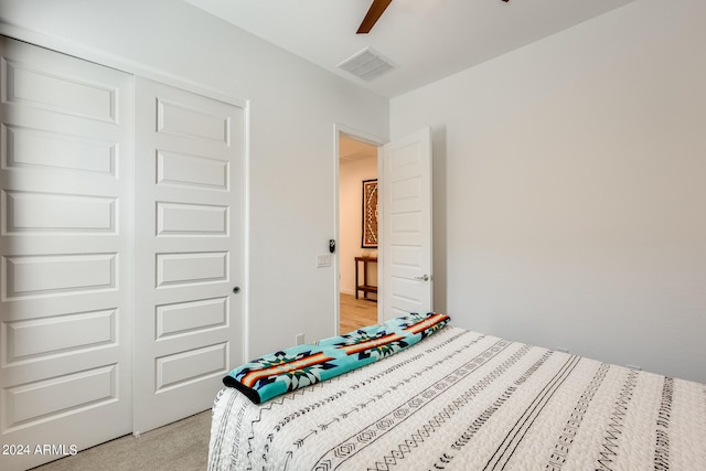 bedroom with ceiling fan, a closet, and light carpet