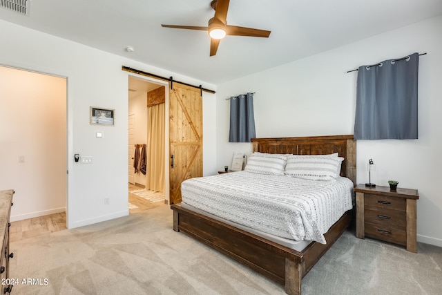 carpeted bedroom with a barn door and ceiling fan