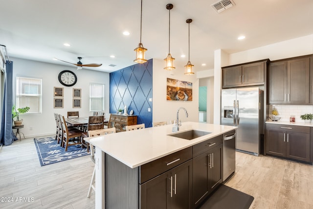 kitchen featuring pendant lighting, light wood-type flooring, dark brown cabinets, sink, and appliances with stainless steel finishes