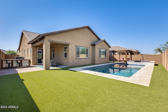 rear view of property with a patio, a lawn, and a fenced in pool