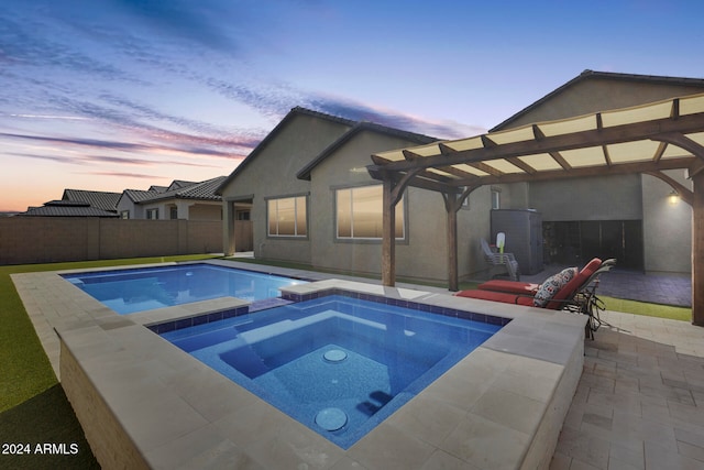 pool at dusk with a patio and an in ground hot tub