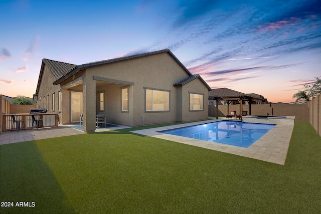 back house at dusk with a lawn, a patio, a fenced in pool, and a gazebo