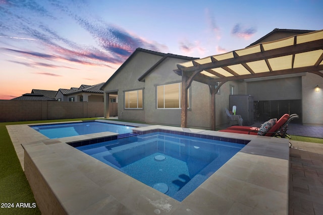 pool at dusk with a patio and an in ground hot tub