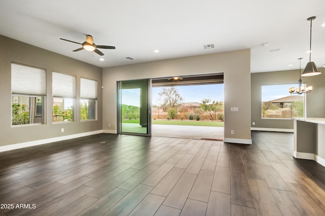 empty room featuring ceiling fan with notable chandelier