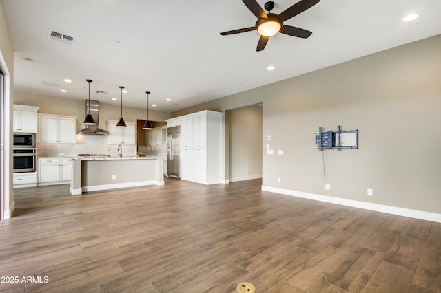 unfurnished living room with hardwood / wood-style flooring, sink, and ceiling fan