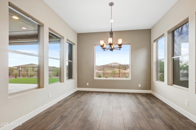 unfurnished dining area with dark wood-type flooring and a chandelier