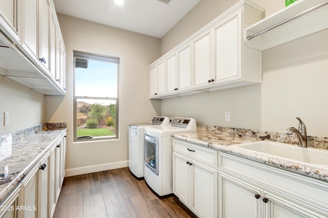 clothes washing area with cabinets, sink, dark wood-type flooring, and washing machine and clothes dryer