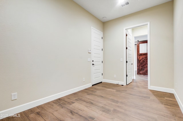 empty room with light hardwood / wood-style floors and a barn door