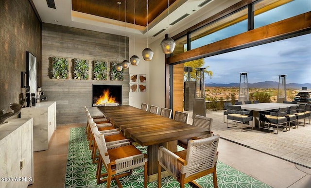 dining area featuring exterior fireplace, a raised ceiling, a high ceiling, and a mountain view