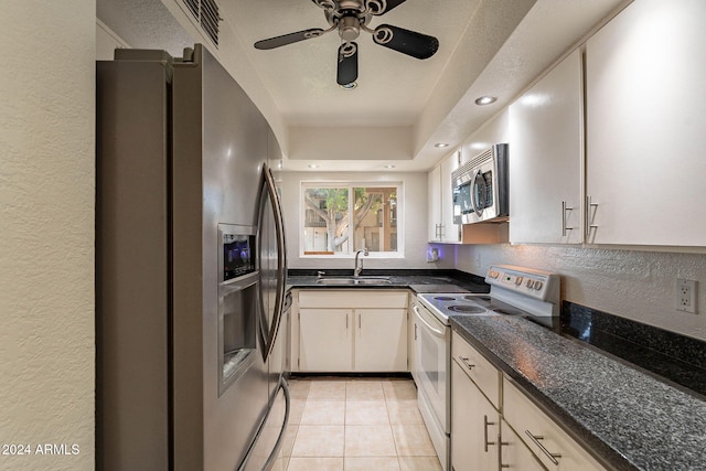 kitchen with dark stone counters, stainless steel appliances, ceiling fan, sink, and light tile patterned flooring